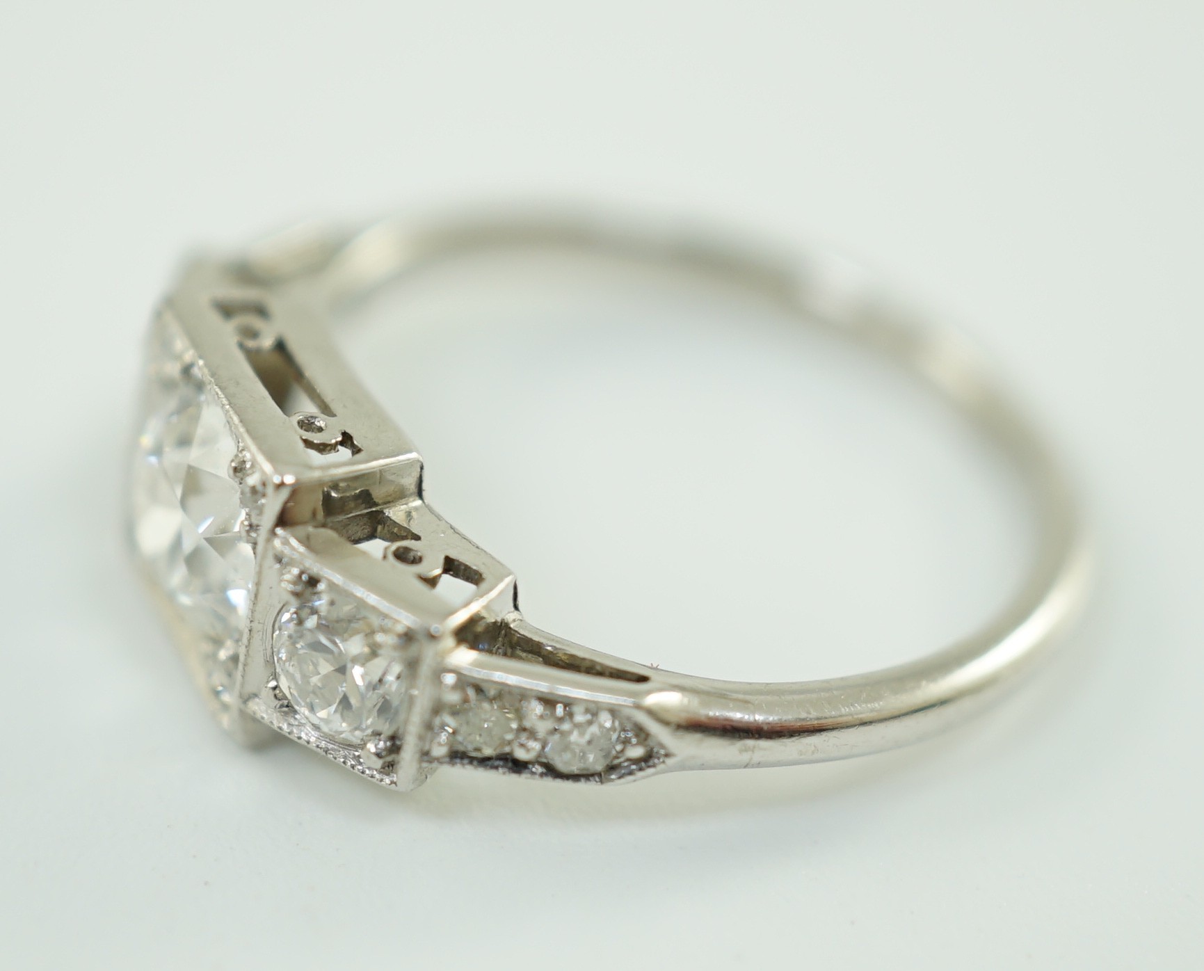 A platinum and millegrain set three stone diamond ring, with diamond set shoulders